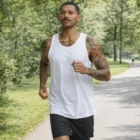 Tattooed man jogging in park wearing Authentic Singlets and black shorts.