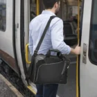 Man with a Delta Checkpoint-Friendly Computer Bag 11L boarding a train.