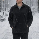 A man in a snowy park wears a dark Winter Fleece Pullover With Zip, hands in his pockets.