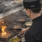 Chef wearing CulinCaps cooks vegetables in a pan over flames in a busy kitchen.
