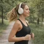 Woman jogs outdoors among trees wearing Pro 2 Purepods headphones and a black tank top.