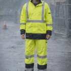 Man in Stormguard (D+N) Hi-Vis Rain Pants and orange hard hat stands in the rain at work.
