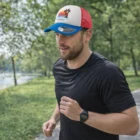 Man jogging in a park, wearing a colorful Flix Polyester Foam Mesh Cap and black t-shirt.