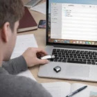 Person inserts a Lexitone Promotional Usb Drive into a laptop while working at their desk.