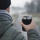 Person in a jacket holding an Arctic Zone Titan Thermal Hp 2 In 1 Coolers 350Ml outdoors.