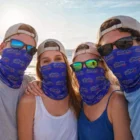 Four people on a beach wearing sunglasses, hats, and Deina Coolmax Bandanas – Adult Large.