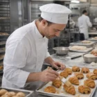 Elgin Baker wears Elgin Baker's Berets and brushes glaze on pastries in a commercial kitchen.