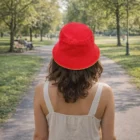Woman in a Brushed Cotton Bucket Hat With Sandwich Trim and white dress walks down a tree-lined path.