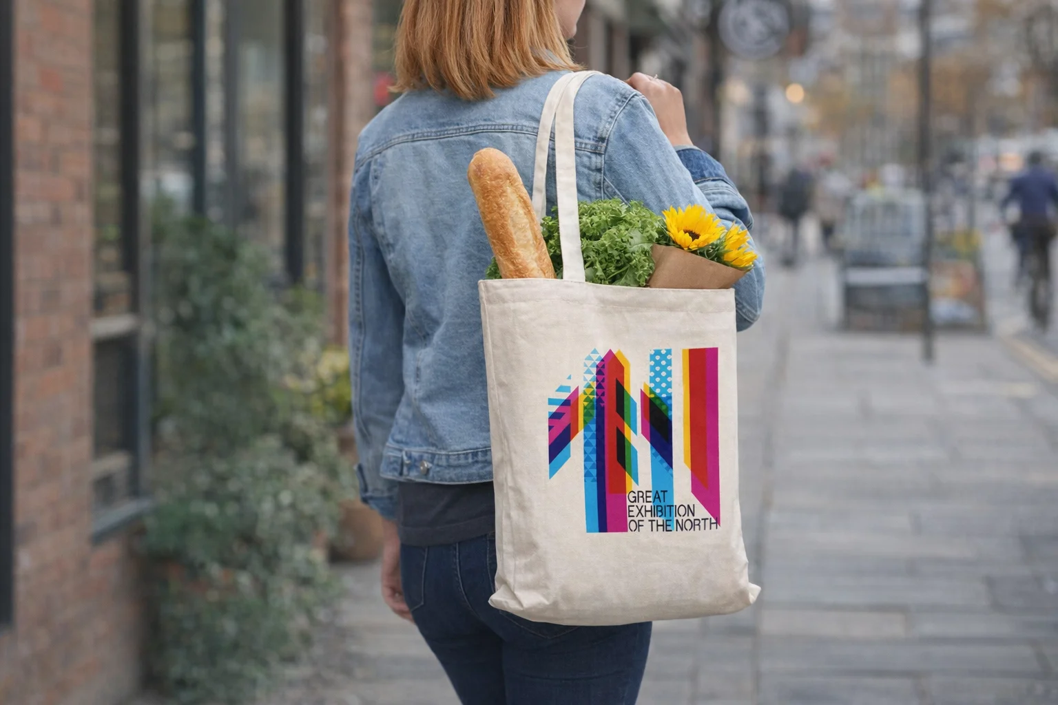 Woman with Lewes Eco Event Bags Medium 280Gsm carrying groceries and flowers on city sidewalk.