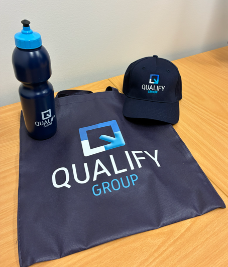 Dark blue Qualify Group tote, hat, and water bottle—perfect for event delivery planning needs.