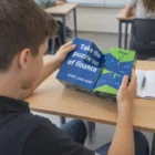 Student holding a Fold Out Magic Square Cube with "Take the puzzle out of finance" text.