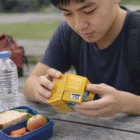 Young man studies a yellow cube with Fold Out Paper Credit Cards at a picnic table.