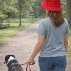 Woman wearing Bim Bucket Hats With Toggle walks a black and white dog on a park path.