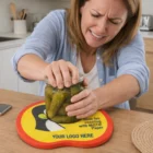 Woman using Jar Openers to open a jar of pickles on a colorful kitchen coaster.