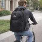 Person riding a bicycle, wearing a black High Sierra Freewheel Pro Rpet Backpack.