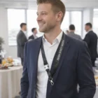 Smiling man in suit at event wearing Imitation Leather Lanyards printed with YOUR LOGO HERE.