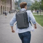 Person with a gray Bergen Commuter Backpack walking outdoors on a city pathway.