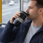 Man drinking from a Falcon Thermal Mug while sitting on public transportation.