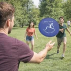 Three friends play with Zemby Folding Flyers in a sunny park, laughing and enjoying the day.