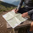 Person on a bench marks a route in the mountains using 2Km Distance Pens.