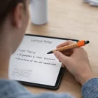 Someone writes biology notes on a tablet using a stylus and Spinner Pens at their desk.