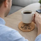 Person holding a coffee mug over Round Cork Villa Coasters on a table.