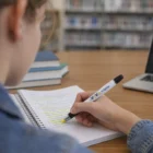Person using Zonko Stylus Pen And Highlighter to mark notes in a notebook at the library.
