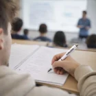 Student uses Viva Solid Colour Brandable Ball Pens to take notes during a classroom lecture.