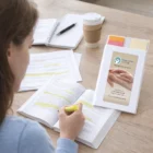 Woman highlights a book at her desk with coffee and a Personalised Notebook With Flags.