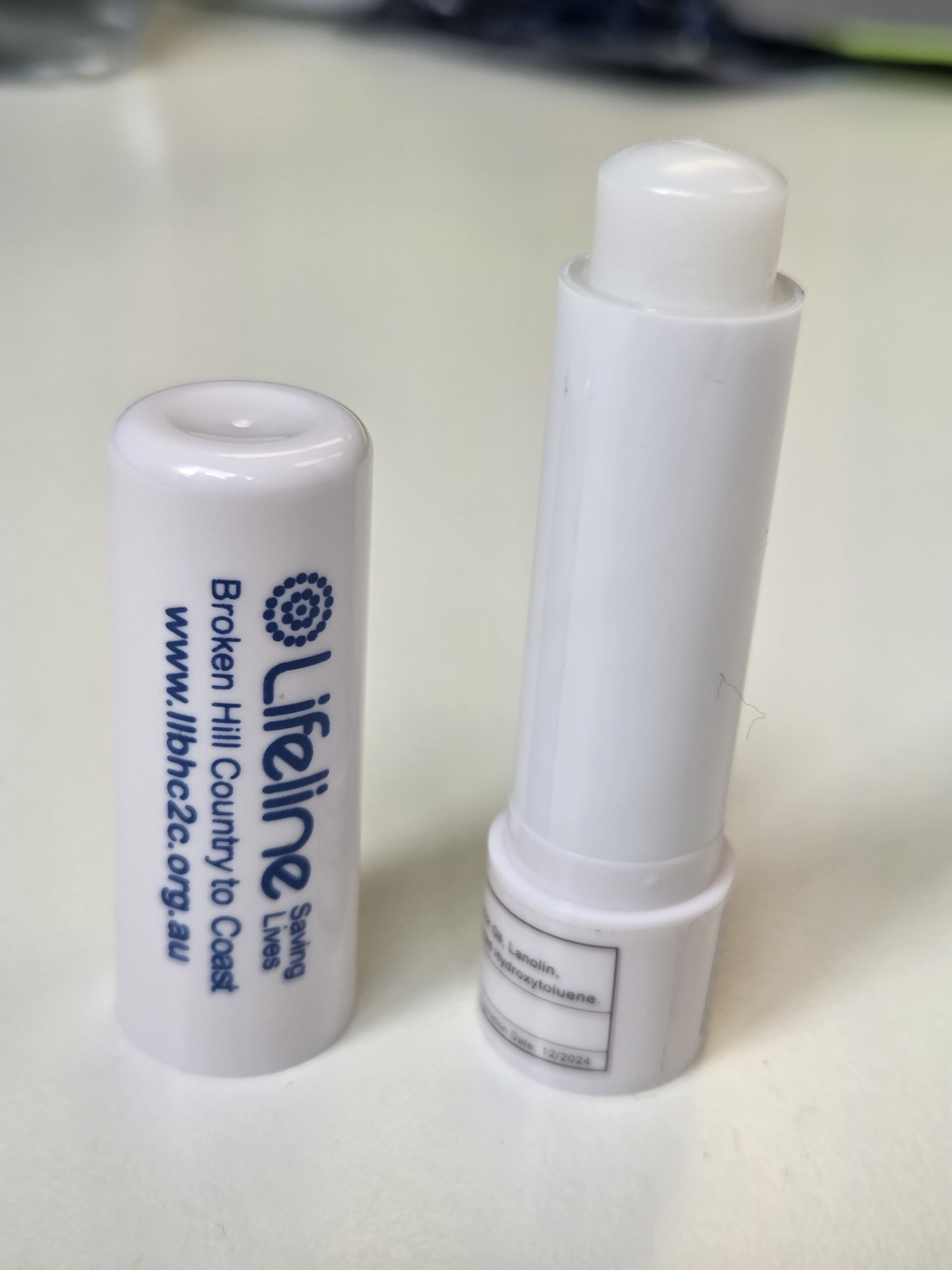 White lip balm tube labeled Lifeline with cap removed, on a white surface.