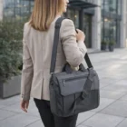 Woman in a beige blazer with a Frymont Briefcases bag outside an office building.