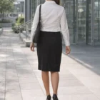 Woman in business attire wearing Lined Skirts, walking on a city sidewalk, view from behind.