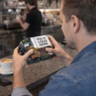 Man holding a Magic Folding Cubes 6Cm at a café counter with coffee and smartphone nearby.