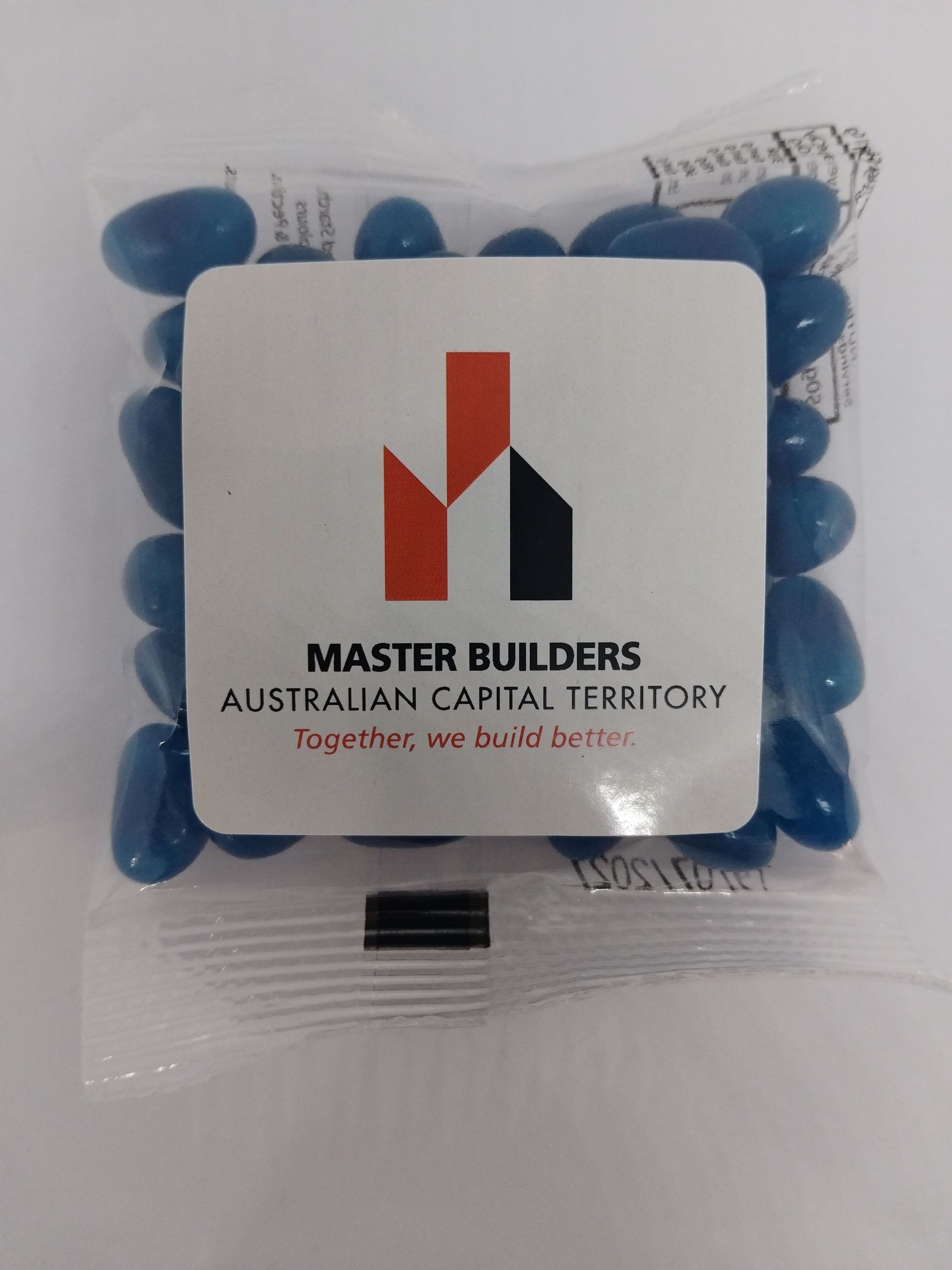 A packet of blue jellybeans featuring a Master Builders ACT logo sticker on the front.