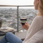 Woman relaxing on a balcony with Plastic Wine Resort 200Ml, overlooking the cityscape.