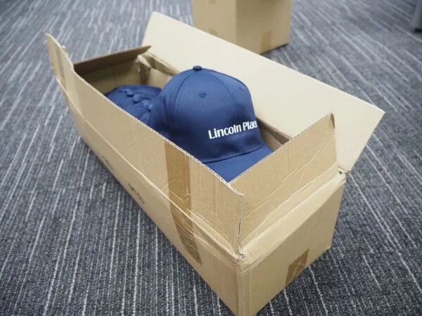 Blue cap with Lincoln Plaza text in box—order bulk to avoid delays on your next shipment.