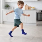 Boy in Crew Kiddie Gripper Socks joyfully skipping on the kitchen floor.