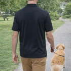 Man in a Bamboo Mens Customised Shirt walks a golden retriever on a park path, seen from behind.
