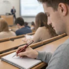 Student writing in a notebook with a Parker Vector Series pen in a college lecture hall.