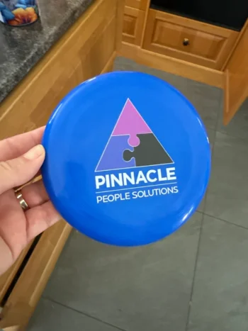 A hand holds a blue frisbee—an ideal event item for all age groups at your next event.