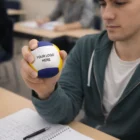 Person holding Stress Ball Hackey Sacks with your logo at a desk with notes and hackey sacks.