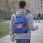 Man with Nylon Tech Travel Drawstring Bag holds notebook, coffee while walking on campus.