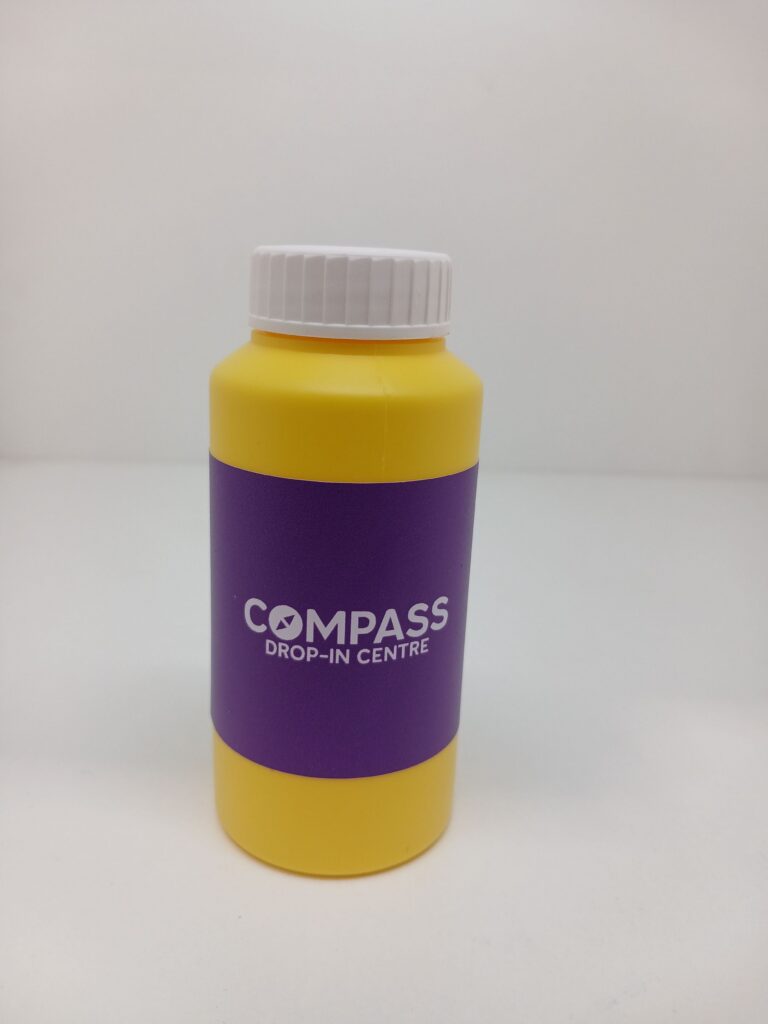 A yellow bottle with a purple label reading COMPASS DROP-IN CENTRE at RMIT University, Melbourne.