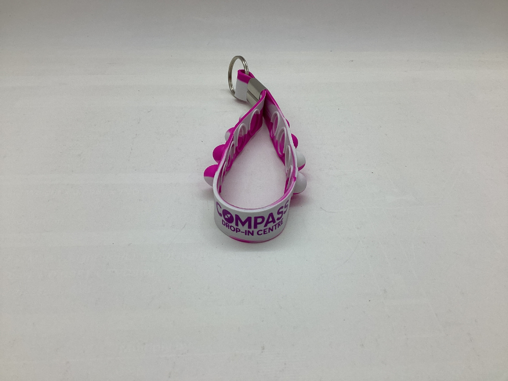 Pink and white COMPASS Drop-In Centre lanyard with metal keyring, at RMIT University.