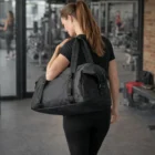 Woman in black workout gear carrying a Stormtech Kitsilano Duffle Bag at the gym.