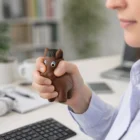 Person squeezing a Stress Toy Horses at a desk with a keyboard and laptop.