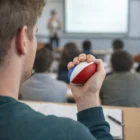 Person holding a Stress Balls FootBalls in a classroom, facing the lecturer.
