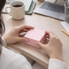 Person holding 75 X 75Mm Colourful Sticky Notes at desk with laptop and coffee.