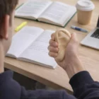 Person squeezing a Customized Stressball Ear while studying at a desk full of books.