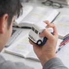 A person squeezes a StressBalls Truck 104MM while studying with books and notes on a desk.